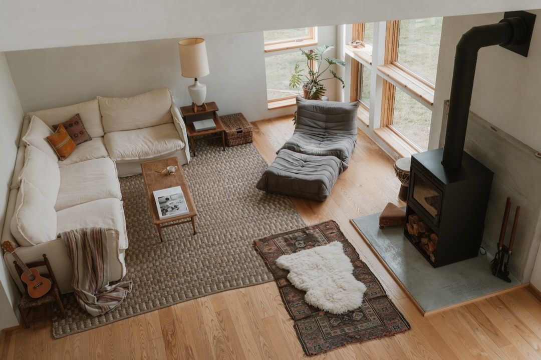 Wohnzimmer mit Holzboden, Teppichen, Textilien und schwarzem Holzofen