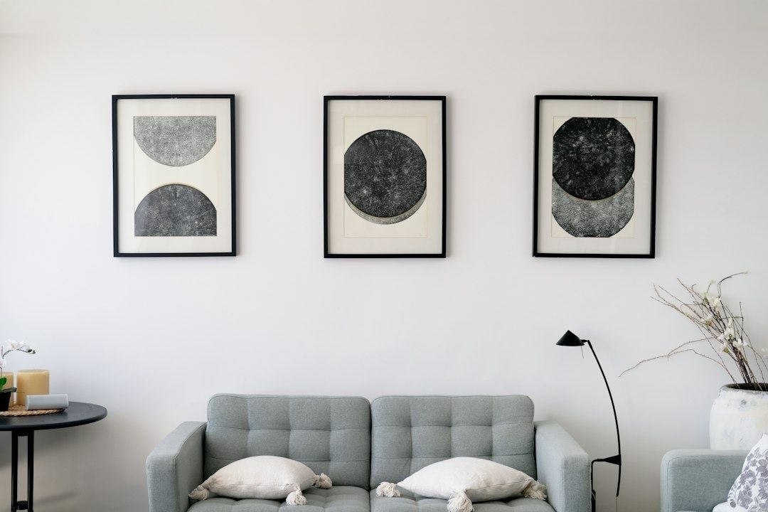 Wohnzimmer mit drei gerahmten, abstrakten Bildern über einem grauen Sofa